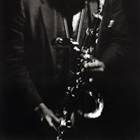 a black and white photograph of a man holding a saxophone