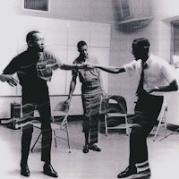 a group of men are dancing in a room