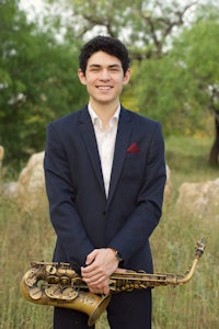 a young man with a saxophone in a field